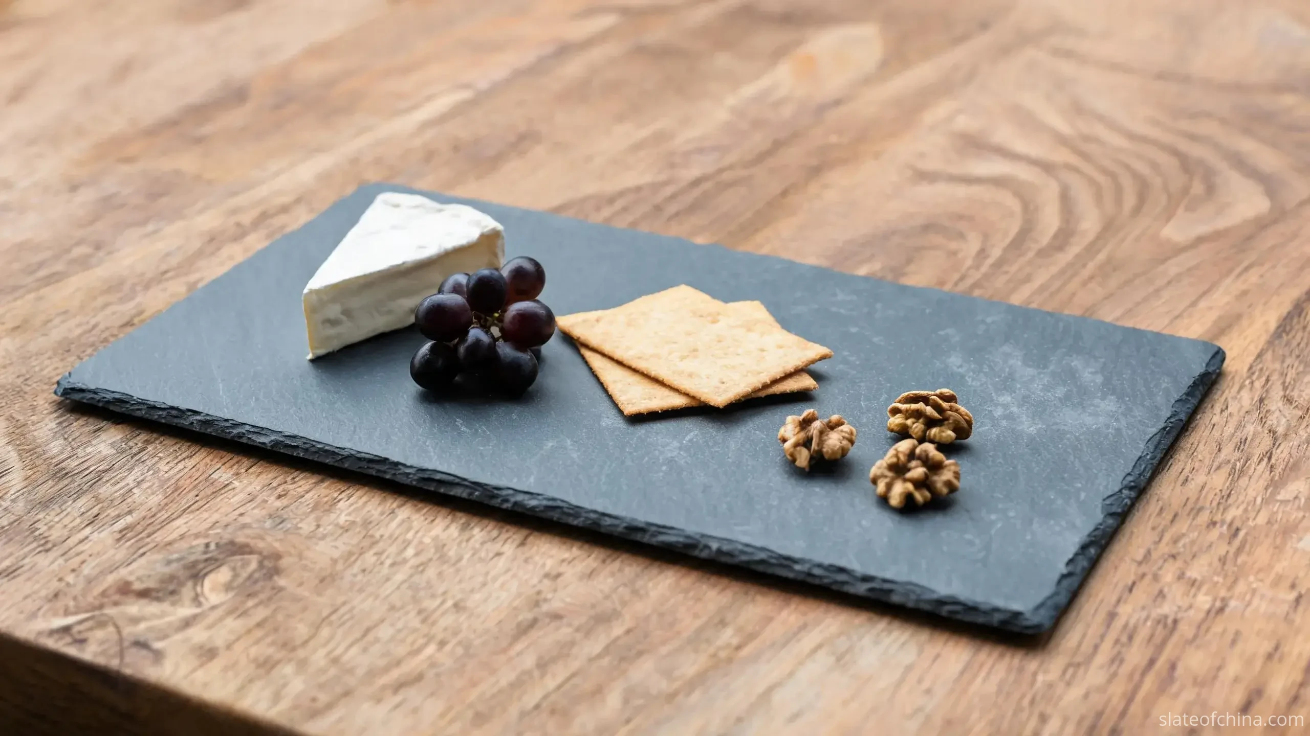 Slate Placemats & Tableware Accessories 2 Illustrative view of a blue-grey slate cheese board presenting cheese, grapes, crackers and walnuts on an oak table