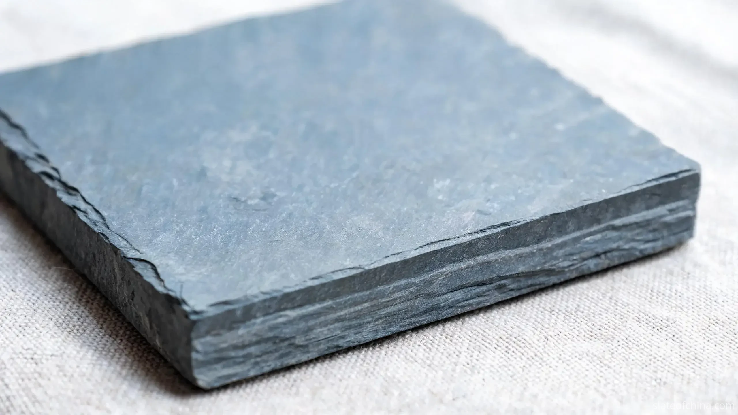 Slate Coasters from Jiujiang 2 Illustrative macro view of a honed slate coaster's top face and sawn side edge showing thickness and faint edge layering