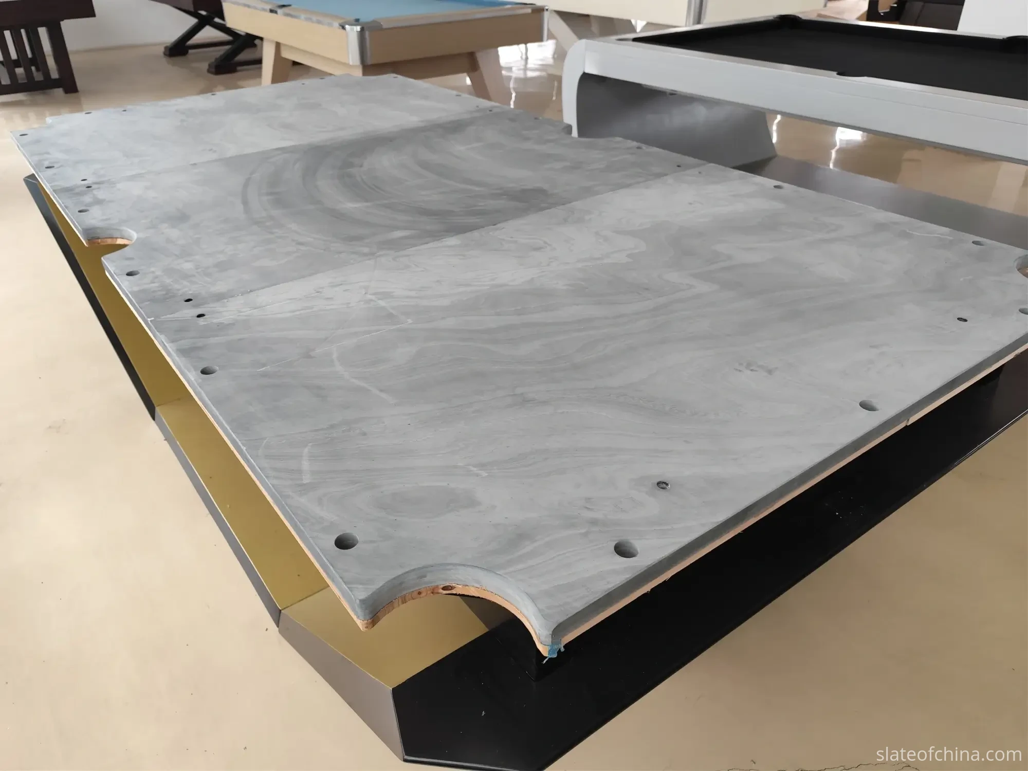 How Slate Flatness Affects Ball Roll 5 Machined billiard slate on a partially assembled table base, the thick 35 mm edge visible at the front pocket cutout with drilled rail mounting holes