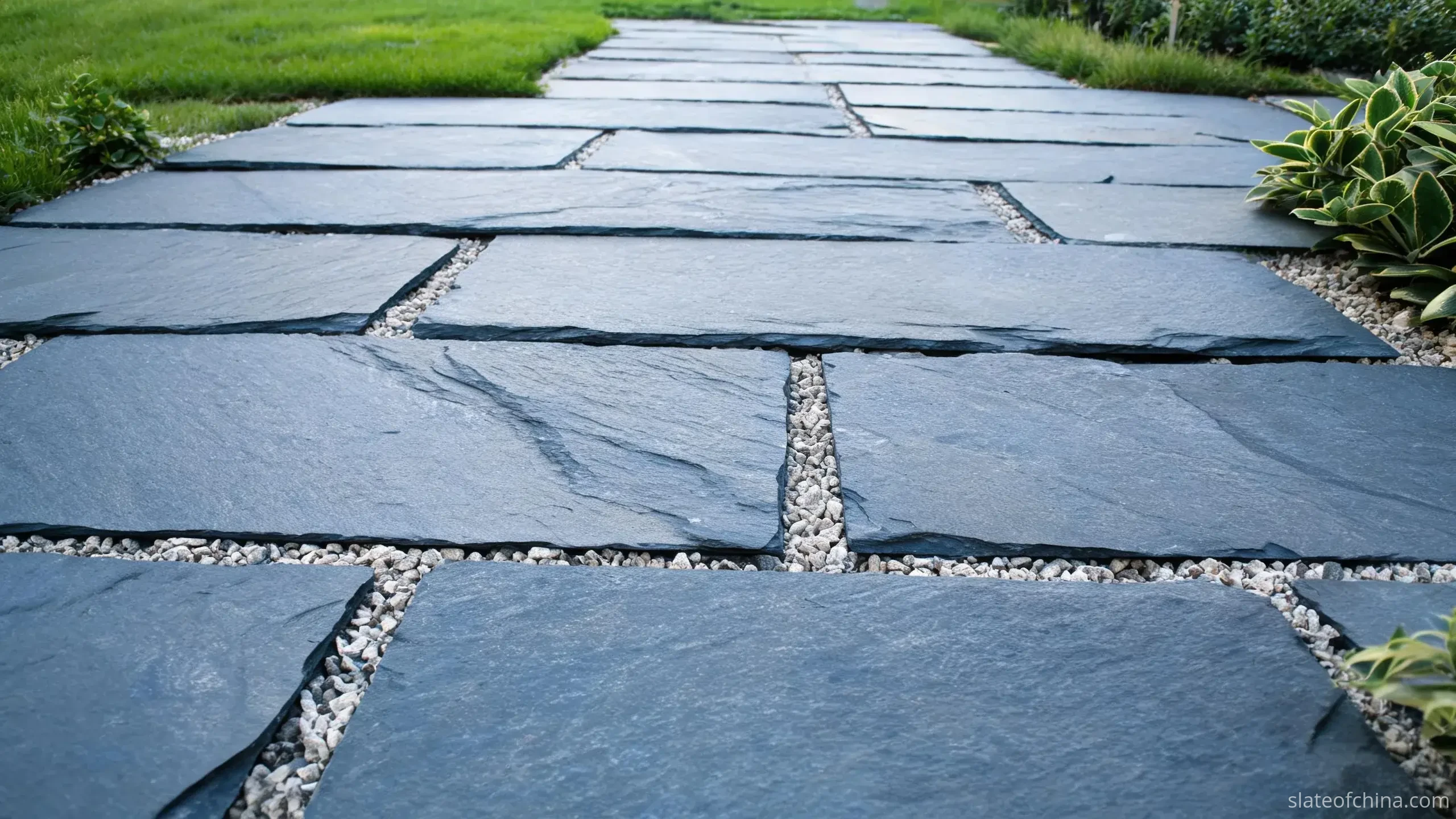 Why Jiujiang Slate Works for Paving 3 Garden path of rectangular blue-grey slate paving running through planted borders toward a distant gate, flags about twice as long as wide in running bond, lawn and planting at the edges