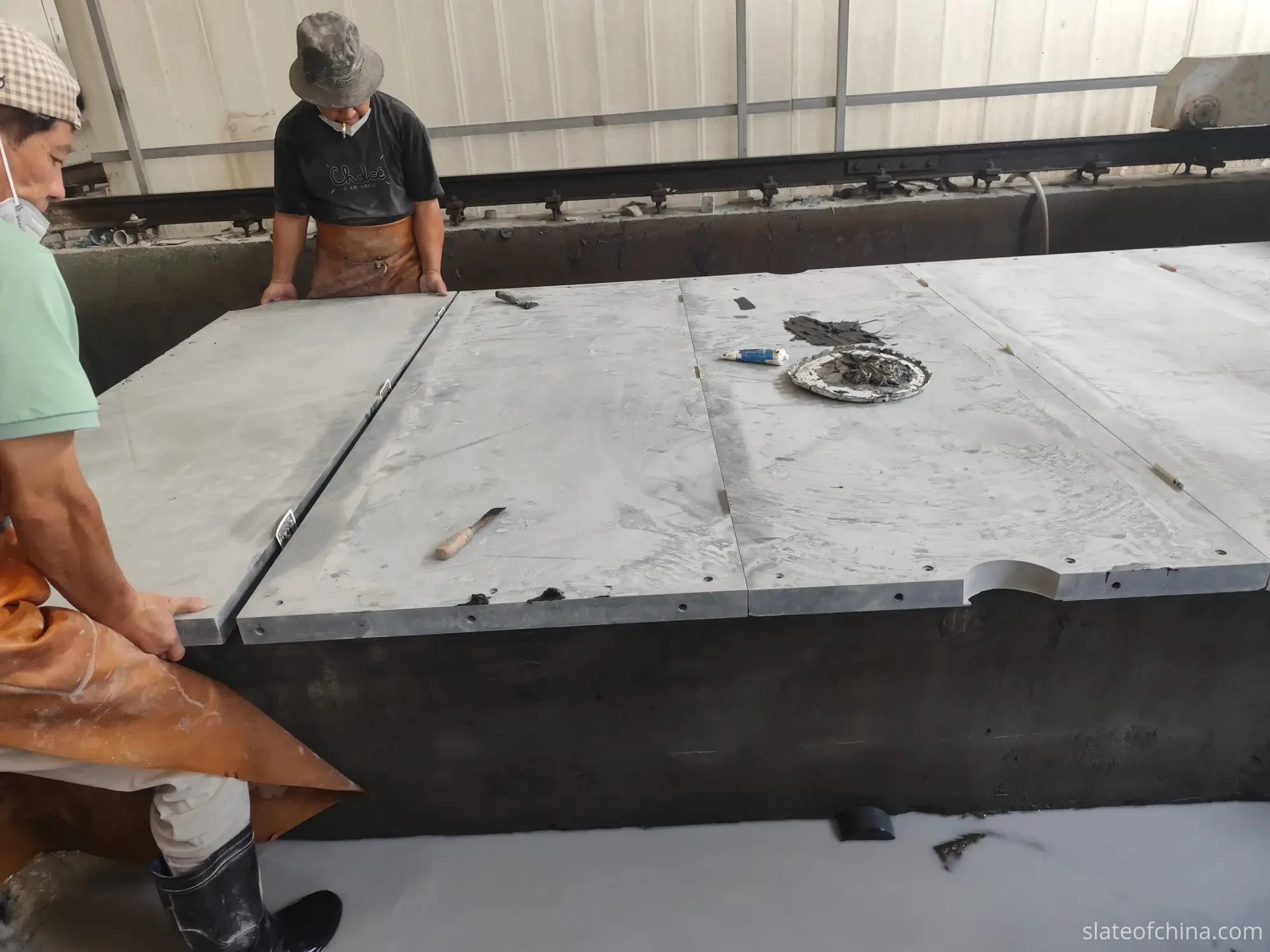 Slate Joint Alignment 2 Workers aligning large machined billiard slate panels edge to edge during assembly, straight finished joint edges meeting tightly