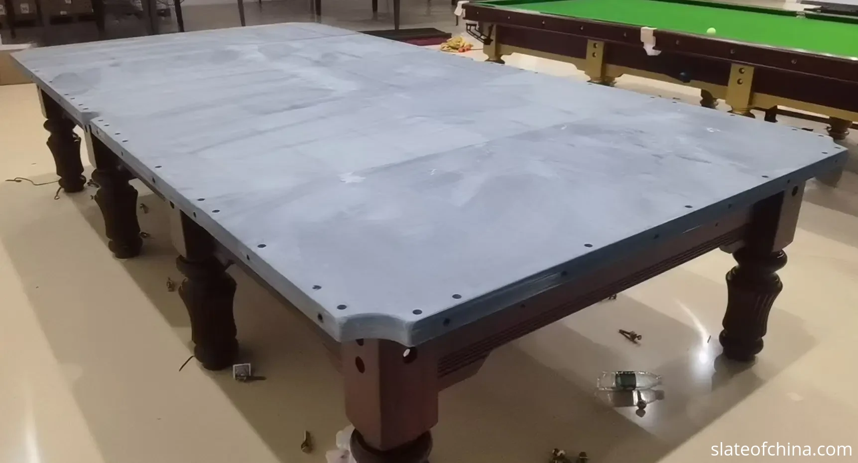 Snooker slate five-piece set joints Real factory photo of a five-piece natural slate bed assembled on a table frame, four straight joint seams running across the bed before the cloth is fitted