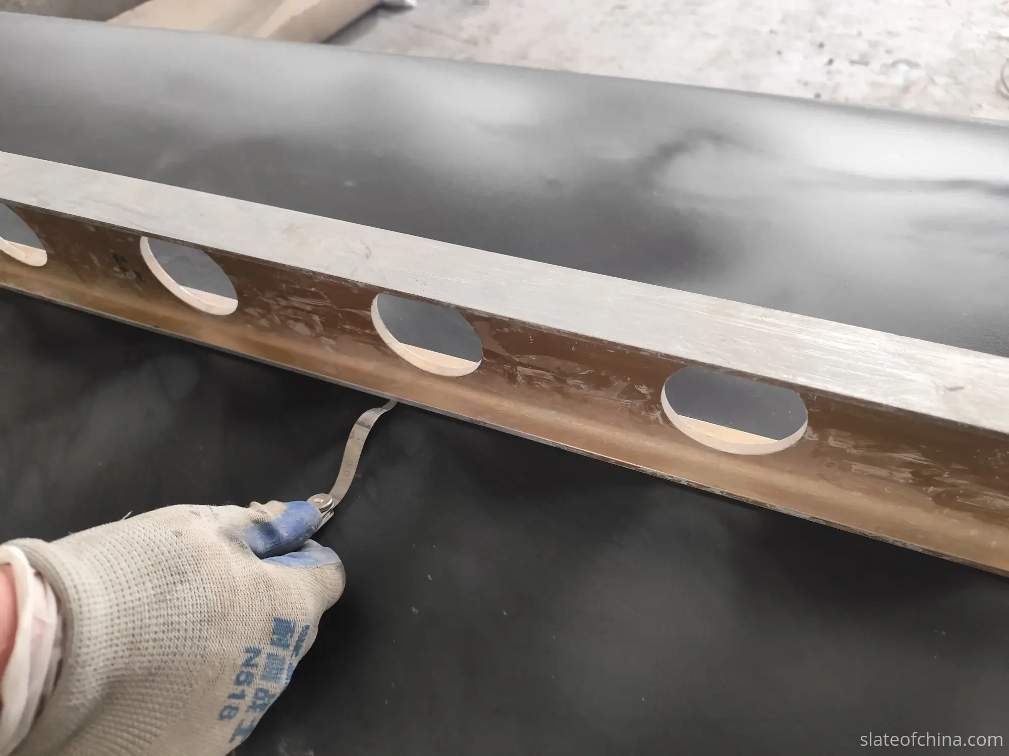 Straightedge and feeler gauge flatness check on ground slate Inspector using straightedge and feeler gauge to check slate surface flatness