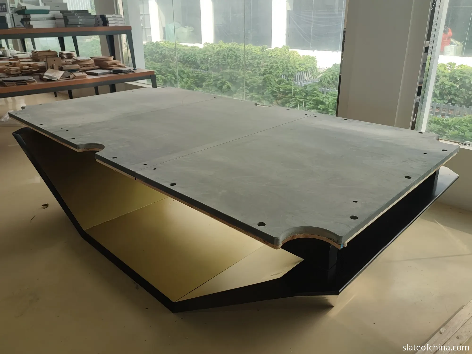 Glossary of Billiard Slate Terms 1 Three-piece billiard slate bed assembled on wooden pallets in a workshop, seams visible