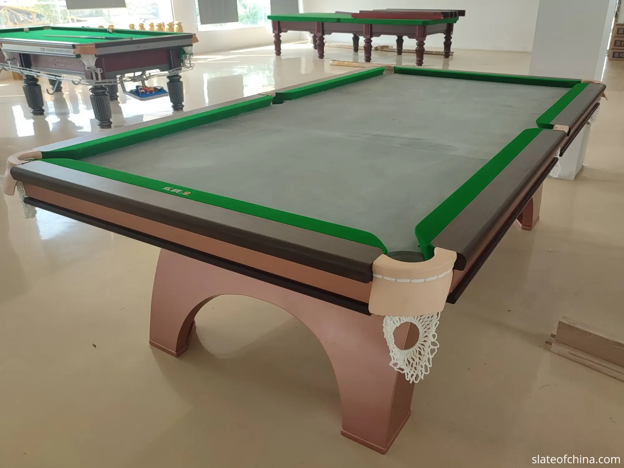 Real photo of a pool table mid-assembly: the three-piece natural slate bed fitted on the frame, rails installed, cloth not yet applied
