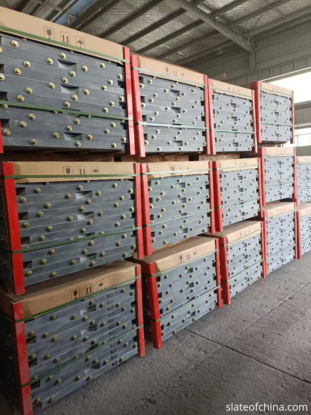 Tournament slate batch sets in export warehouse Real factory photo of matched sets of slate billiard bed panels strapped, bolted and stacked on wooden pallets in a warehouse, staged for one export order